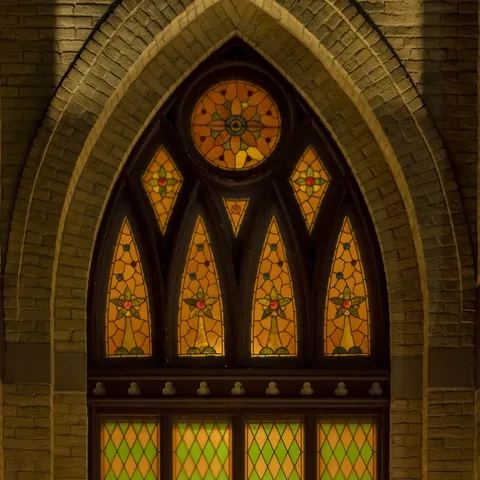 Ornate stained-glass window framed by a brick arch