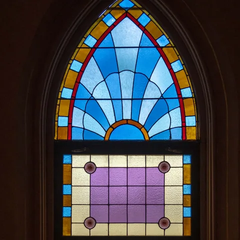 Blue and purple stained-glass window with an arched top