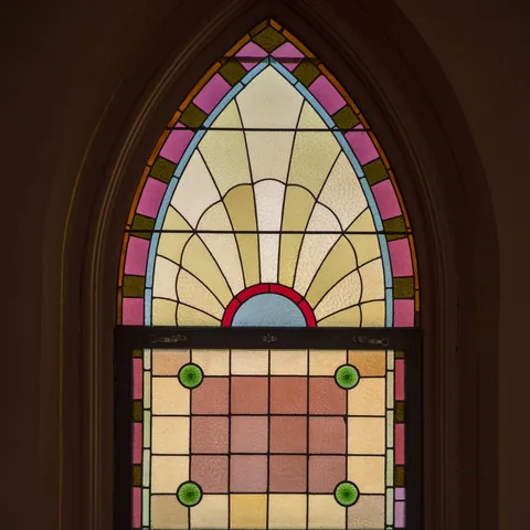 Arched stained-glass window with soft pink and yellow panes