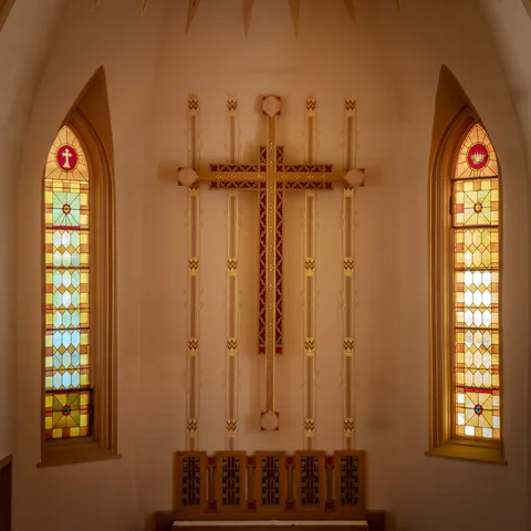 Sanctuary cross framed by two stained-glass windows